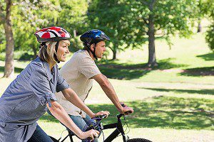 Photo of couple riding bikes through a park
