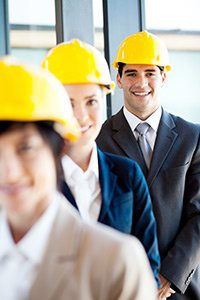 Group of young business people in suits and hardhats.