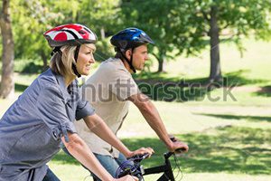 Photo of couple riding bikes through park