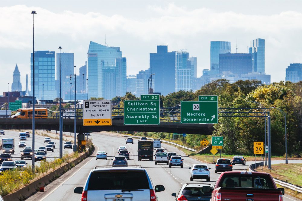 Image of cars driving on a highway with Boston skyline in the background