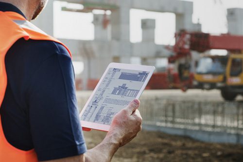 Photo of a construction worker using a tablet device on construction location - Business Liability Insurance in Greater Boston & Massachusetts