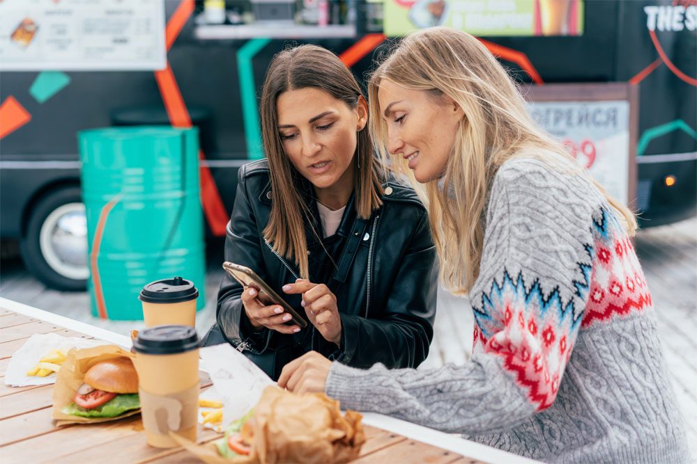 Image of two women looking at a cellphone during a meal