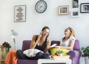 Photo of two women laughing sitting on a purple couch