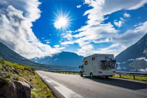 Photo of an RV driving on a road on a bright day