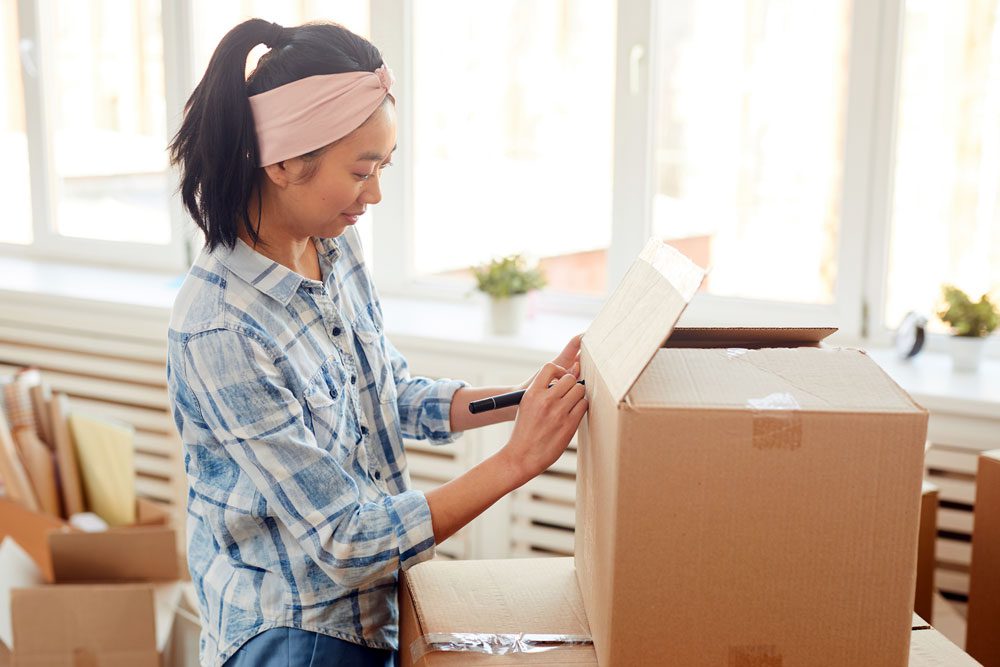 Image of a young woman packing a cardboard box